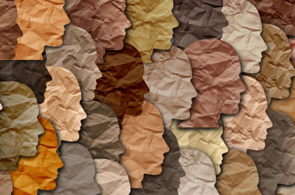 paper cut outs of face silhouettes in many shades representing diversity and multiculturalism