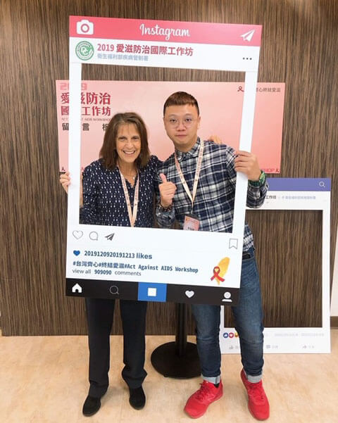 Two people pose behind a cardboard instagram frame
