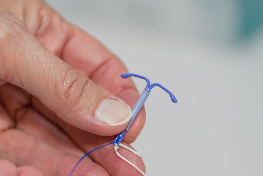 A close-up view of a hand holding an intrauterine device