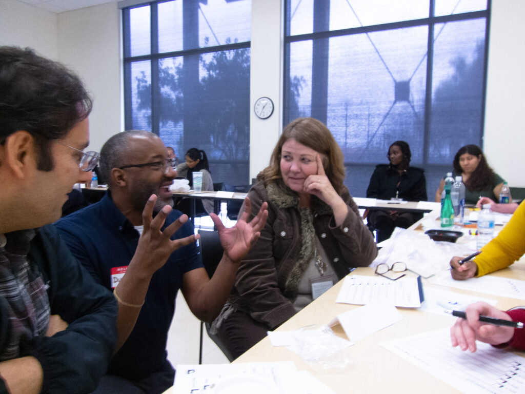 Three people at a table with the middle person talking while the other two are listening