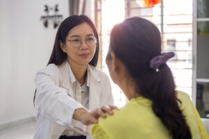 A female doctor puts her hand on a patient's shoulder.