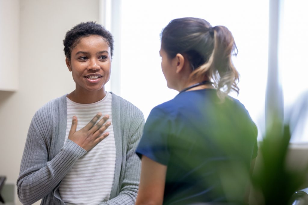 Nurse with a female patient. The patient is smiling with her hand over he heart.