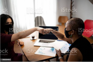 Two people wearing face masks fist bump